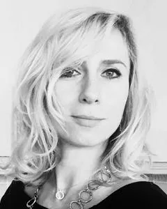 Black-and-white headshot of a woman with wavy blonde hair and a necklace.