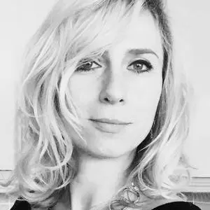 Black-and-white headshot of a woman with wavy blonde hair and a necklace.