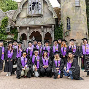 Graduates pictured in their cap and gowns in front of The Curse of Alton Manor