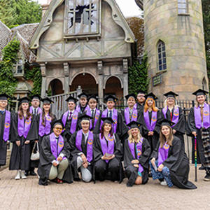 Graduates pictured in their cap and gowns in front of The Curse of Alton Manor 