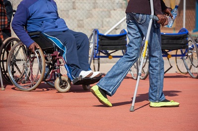 An image of someone in a wheelchair and someone using a crutch
