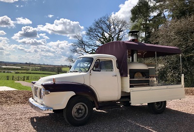 Vintage cream pickup truck converted into a mobile catering unit under a blue sky.