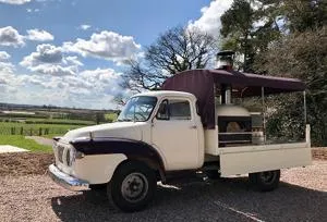 Vintage cream pickup truck converted into a mobile catering unit under a blue sky.