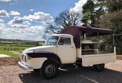 Vintage cream pickup truck converted into a mobile catering unit under a blue sky.