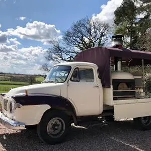 Vintage cream pickup truck converted into a mobile catering unit under a blue sky.