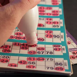A hand with a dabber filling in a bingo card