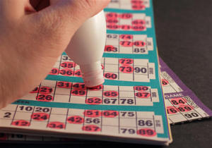 A hand with a dabber filling in a bingo card 
