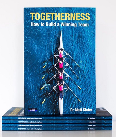 Blue book cover titled 'Togetherness: How to Build a Winning Team' displayed above a stack of copies.