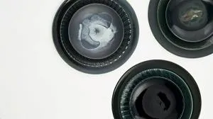 Three dark ceramic bowls with swirling grey and white centres arranged on a pale surface.