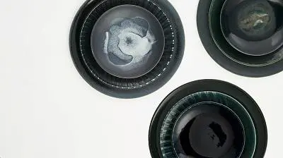 Three dark ceramic bowls with swirling grey and white centres arranged on a pale surface.