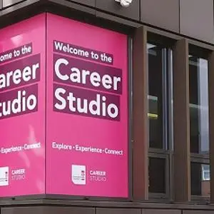 Campus windows wrapped in magenta signs reading 'Welcome to the Career Studio.'