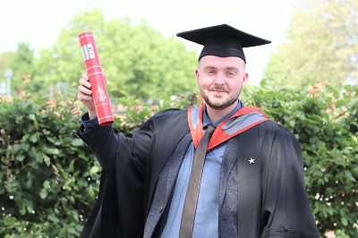 Carl Smith holding a scroll in his graduation robes