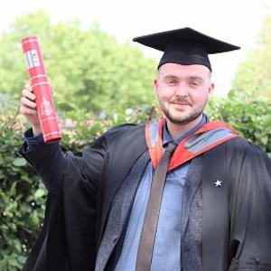 Carl Smith holding a scroll in his graduation robes