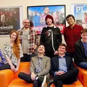 Animation studio team poses together in an office decorated with colourful film posters.