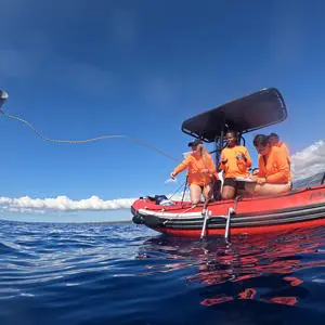 Professor Claire Gwinnett throwing a sampling bucket of the side of a boat on the sea