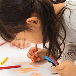 A child drawing a picture with colourful crayons