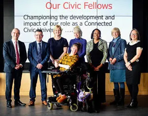 Six Civic Fellows, including a wheelchair user, pose beneath a presentation screen.