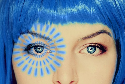 Close-up of a blue-haired woman with a blue and yellow sun design painted around one eye.