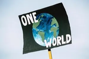 Handmade protest sign reading 'ONE WORLD' around a painted globe.