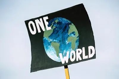 Handmade protest sign reading 'ONE WORLD' around a painted globe.
