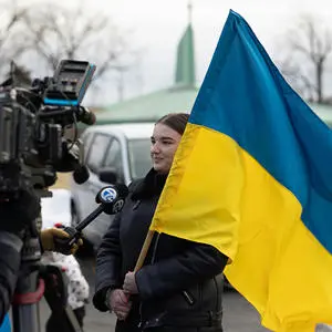 A television crew interviewing a women holding the Ukraine flag