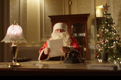 Santa sat at a desk reading a child's letter