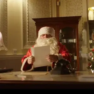 Santa sat at a desk reading a child's letter