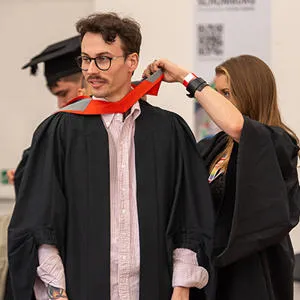A student being dressed in a graduation gown