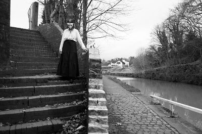 masked figure on steps near canal