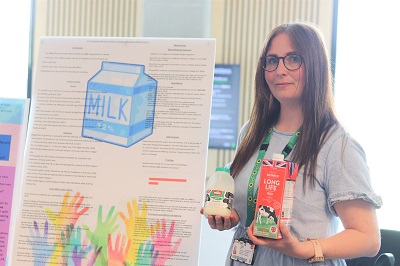 Emma Green holding milk bottles in front of her project poster