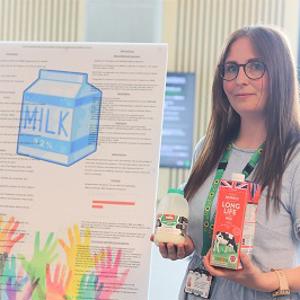 Emma Green holding milk bottles in front of her project poster