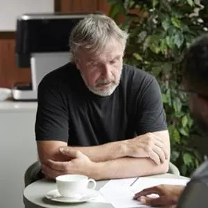 Elderly man in meeting situation with another man.