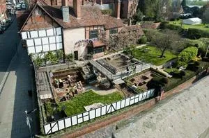 Aerial view of an archaeological excavation surrounding a historic timber-framed building.
