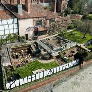 Aerial view of an archaeological excavation surrounding a historic timber-framed building.