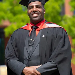 A smiling man wearing a graduation cap and gown