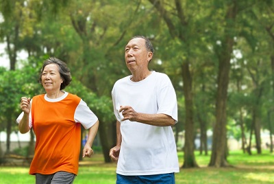 An older couple jogging in a park 