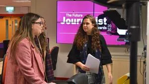 Two women talk in a studio beside a screen reading 'The Future Journalist Awards 2020.'