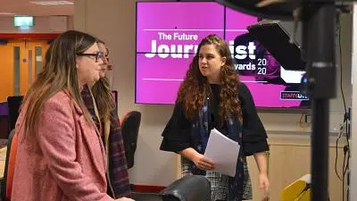 Two women talk in a studio beside a screen reading 'The Future Journalist Awards 2020.'
