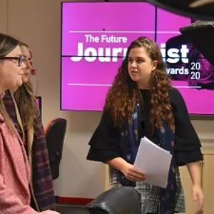 Two women talk in a studio beside a screen reading 'The Future Journalist Awards 2020.'