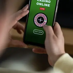 Hands holding a mobile phone with an online casino game on the screen