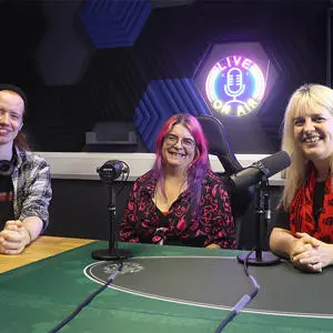 Three people sat in a podcast recording studio