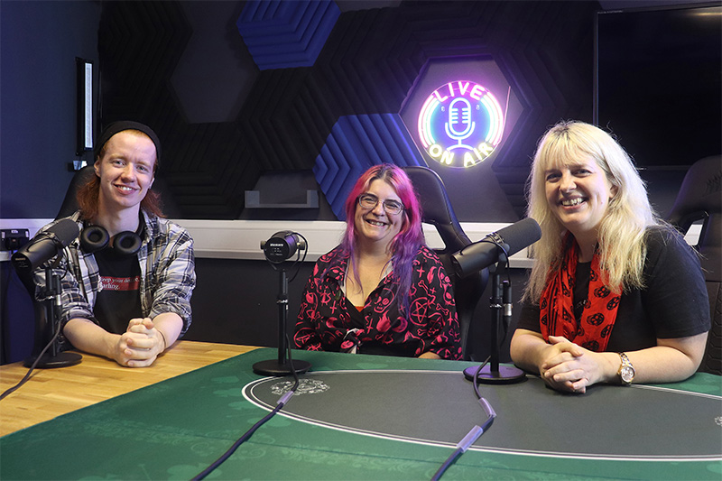 Three people sat in a podcast recording studio