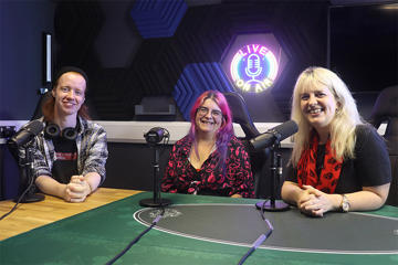 Three people sat in a podcast recording studio