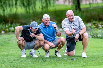 Three  men with golf culbs on the golf course