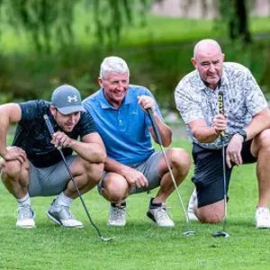 Three men with golf culbs on the golf course