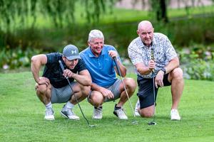 Three  men with golf culbs on the golf course