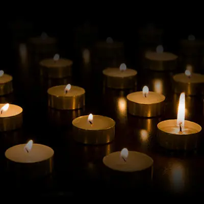 Rows of small memorial candles glow against a black background.