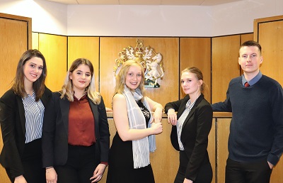 Five members of a student moot court team pose together in a courtroom.