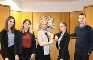 Five members of a student moot court team pose together in a courtroom.