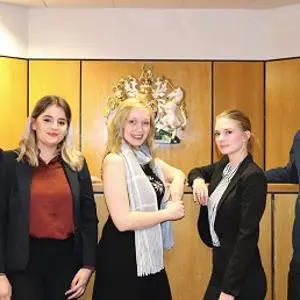 Five members of a student moot court team pose together in a courtroom.